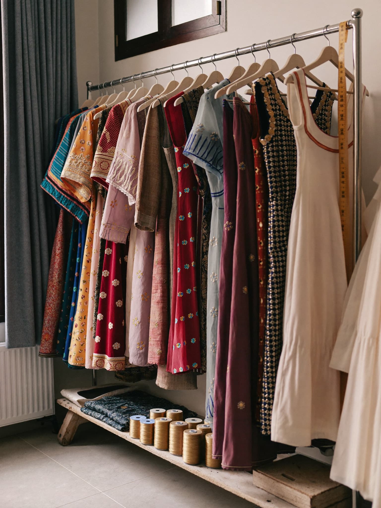 A rack of handmade dresses with gold thread and a tape measure in the Kabul Fashion atelier.