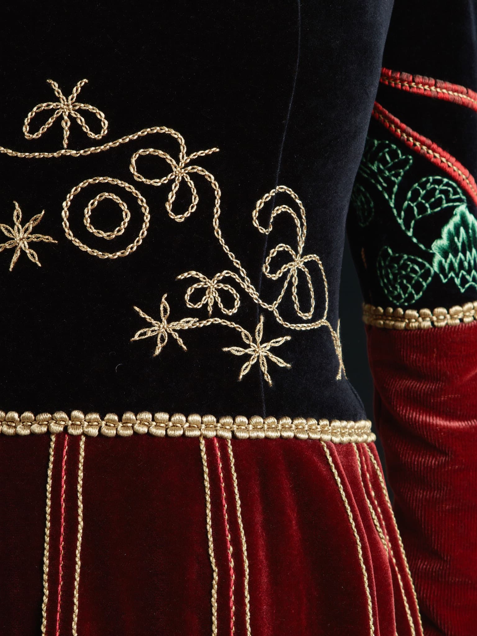 Gold hand embroidery flowing across deep velvet.